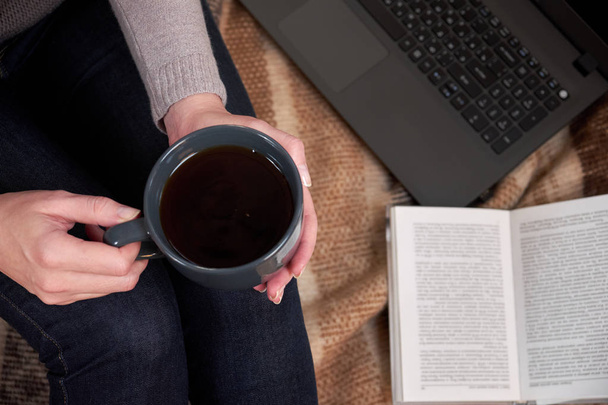 Woman with a Cup of tea, a book,  mittens and a laptop on a blanket. Selective focus - Foto, immagini