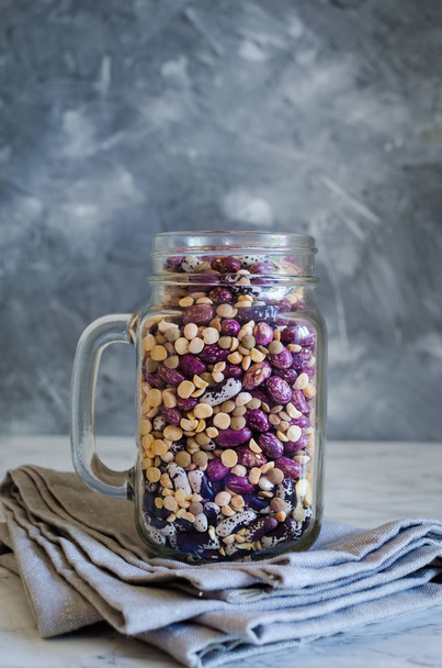 Assortment of dry organic beans and lentils in glass jar on marble table. Variety of raw legumes. Balanced diet, cooking, vegetarian and clean eating concept. Healthy food. - Fotografie, Obrázek