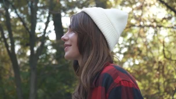 Portrait of a cute hipster girl. Smiling young girl in a plaid shirt and white cap. - Imágenes, Vídeo