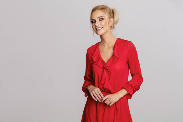 Beautiful smiling blond woman in red dress isolated on gray background - Φωτογραφία, εικόνα