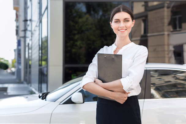 Konsultant dziewczyna z dokumentów stojący w pobliżu nowego samochodu - Zdjęcie, obraz