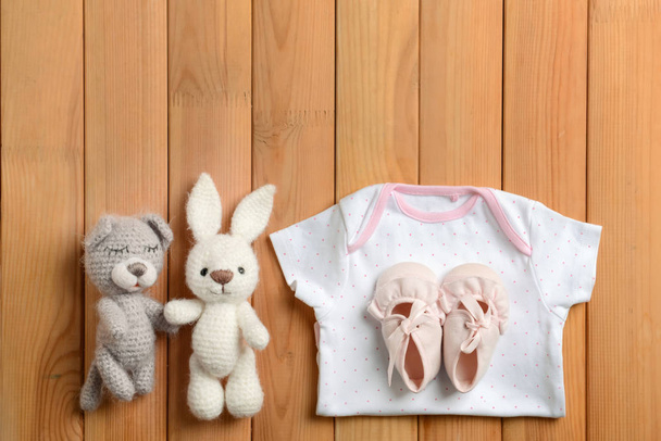Roupas de bebê e brinquedos em fundo de madeira, flat lay
 - Foto, Imagem