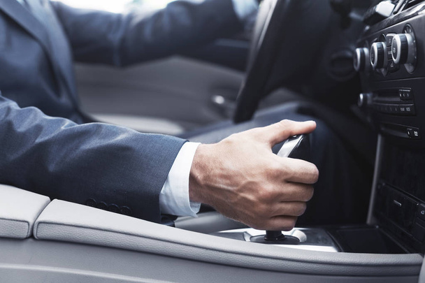 Businessman in suit changing gear in car - Photo, Image