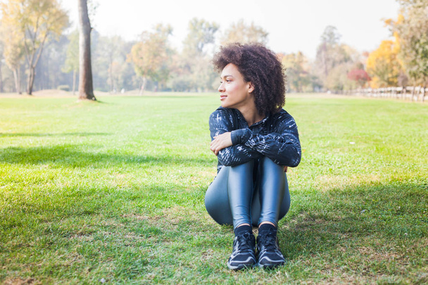 glücklich sportliche afroamerikanische junge Frau entspannen auf grünem Gras im Park nach Outdoor-Workout. - Foto, Bild