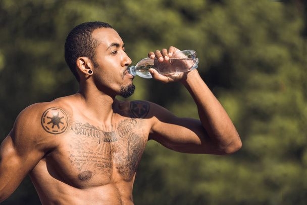 Athletic man drinking water after workout outdoors - Photo, Image