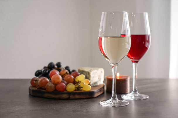 Erilaisia viinejä ja välipaloja sisältävät lasit harmaalla pöydällä
 - Valokuva, kuva