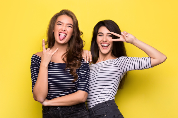 Carefree women fooling around together on yellow background - Photo, Image
