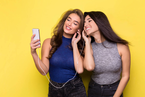 Two women listening music online on smartphone - Fotoğraf, Görsel
