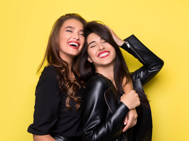 Due belle ragazze che si abbracciano su sfondo giallo
 - Foto, immagini