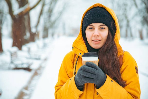 Nainen juomassa kahvia puistossa muotokuva. Juotavaa mukaan. talvella. lämmetä käsite
 - Valokuva, kuva