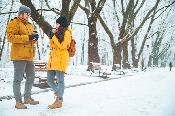 paar wandelen door gesneeuwde stadspark praten socialiseren. romantische datum in de winter. Kerstmis komt eraan - Foto, afbeelding