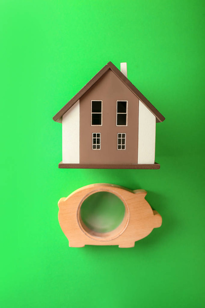 Wooden piggy bank with house model on color background - Photo, Image