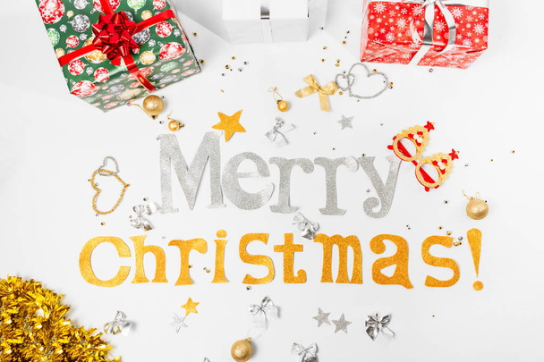 Beschriftung Glückwünsche zu frohen Weihnachten und einem guten neuen Jahr mit Geschenkschachteln und Weihnachtsspielzeug, auf weißem Hintergrund. - Foto, Bild