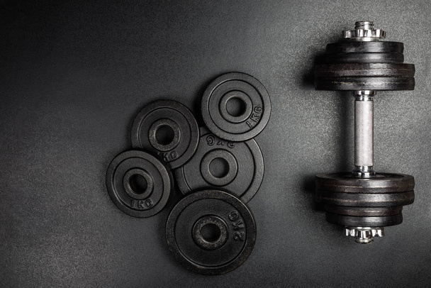 Gym dumbbells with black metal weights 1kg and 2kg on black background with copy sapce, Photograph taken from above. - Photo, image
