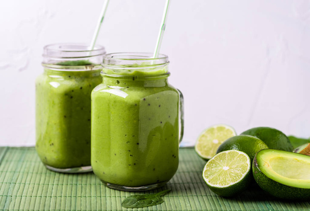 Zelené smoothie na zeleném pozadí s avokádem, špenát, citron a kiwi na pravé straně. - Fotografie, Obrázek