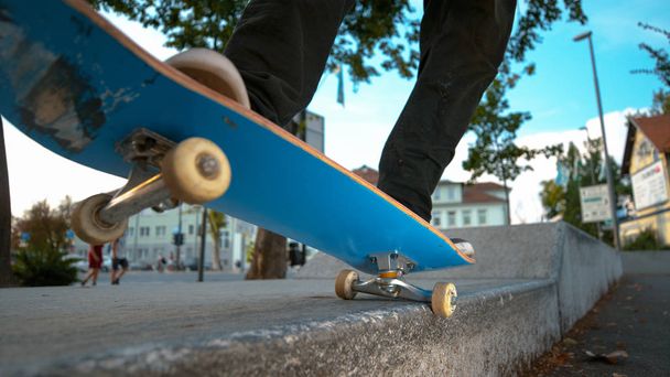 CHIUSURA, DOF: Giovane skateboarder irriconoscibile in pantaloni neri e sneakers macina una sporgenza di cemento nel parco urbano. Fresca coda di pattinatore che macina una sporgenza in un parco panoramico nelle verdi strade della città
. - Foto, immagini