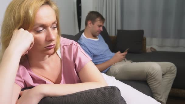 Pár krize. Muž a žena strávit večer v obýváku na gauči. muž používá telefon, Žena je naštvaný, že mu nevěnuje pozornost k ní. - Záběry, video