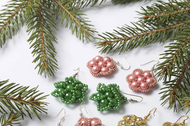 Women's earrings made of beads among the branches of spruce. On a white background. - 写真・画像