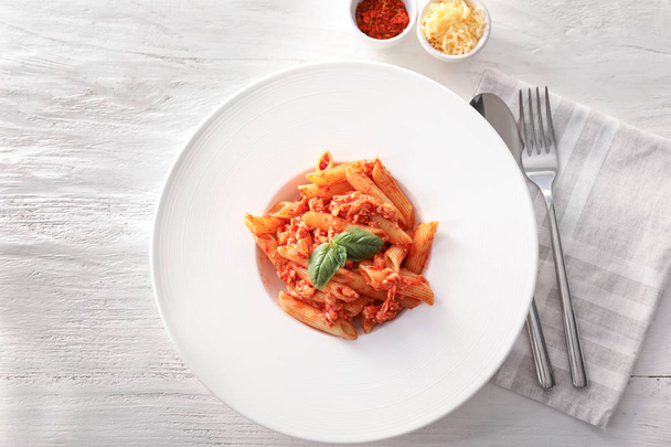 Tasty penne pasta with tomato sauce on plate - Foto, afbeelding