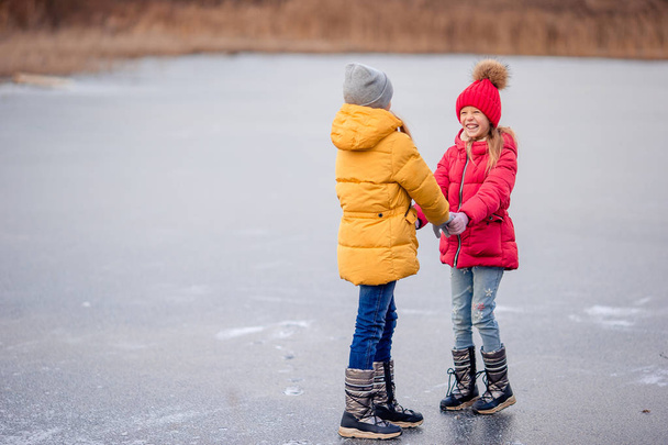 Αξιολάτρευτο μικρό κορίτσια έχουν τη διασκέδαση μαζί στην παγωμένη λίμνη - Φωτογραφία, εικόνα