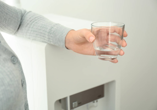 Femme avec verre d'eau près du refroidisseur dans le bureau
 - Photo, image