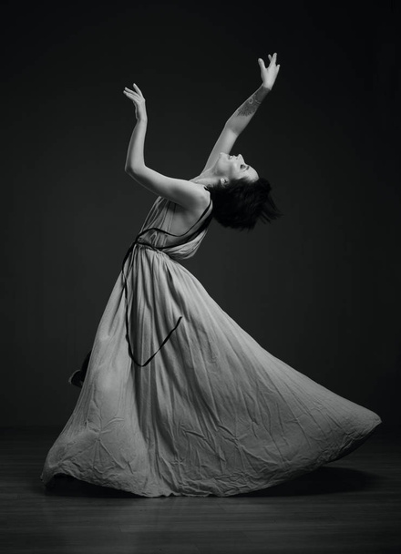 táncoló nő stúdió portré egy sötét háttér fekete-fehérben - Fotó, kép