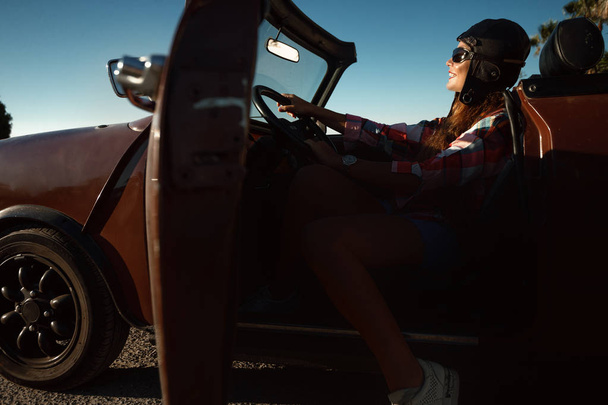 Beautiful young woman sits inside convertible car.  - Фото, изображение