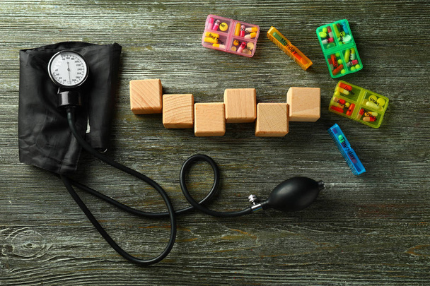 Cubos en blanco con esfigmomanómetro y pastillas sobre fondo de madera
 - Foto, Imagen