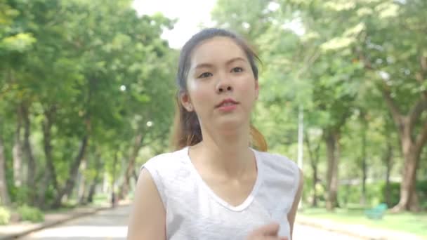Young attractive woman running in the green city park exercising outdoors fitness tracker wearable technology. - Filmmaterial, Video