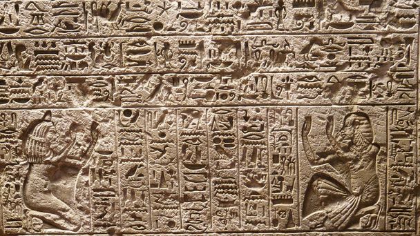 Close-up: Gedetailleerde weergave van prachtige Egyptische symbolen uitgehouwen in een stenen muur. Cool close up van een plaat van steen met traditionele belettering in een museum in Rome. Historische hiërogliefen afgebeeld op rots. - Foto, afbeelding