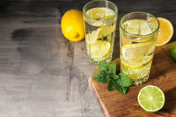Glasses of water with lemon on grey table - Fotó, kép