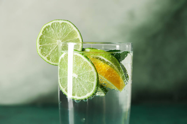 Glass of water with lemon and lime on color background, closeup - Foto, Bild