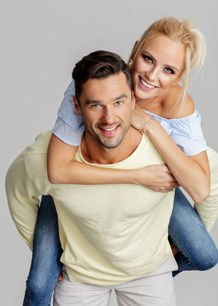 Young smiling man piggyback his beautiful girlfriend - Фото, зображення