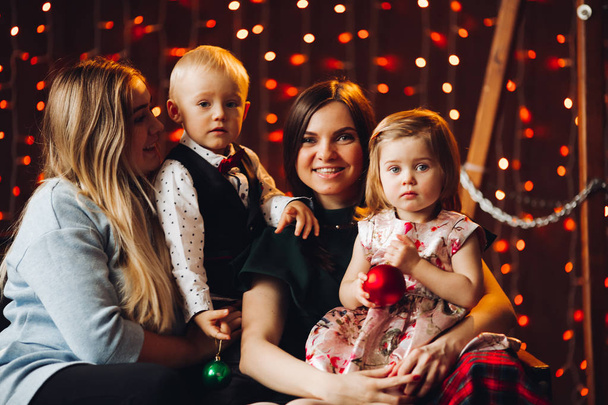 Twee moeders zitten met schattige kinderen kerstcadeautjes. - Foto, afbeelding