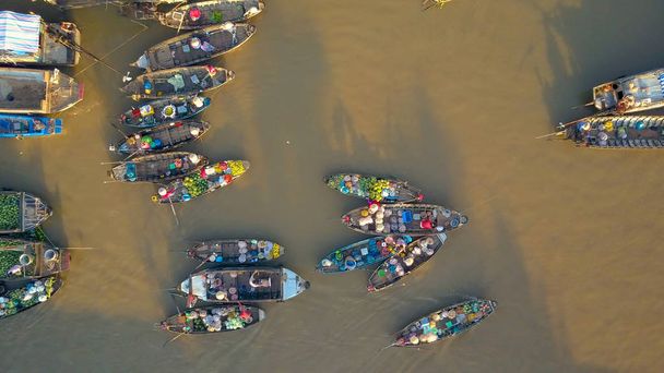 Πλωτή αγορά εμπόρους επιχειρείν από τους ξύλινες βάρκες που επιπλέουν γύρω από το σκοτεινό ποτάμι στο Βιετνάμ. Οι ντόπιοι στην ύπαιθρο Βιετναμέζικα πωλούν τα προϊόντα τους από βάρκες. - Φωτογραφία, εικόνα