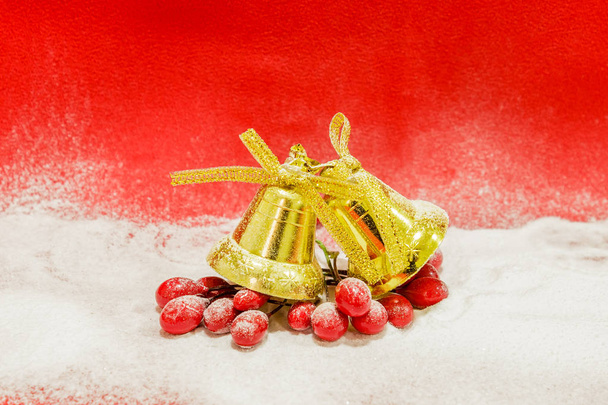 A pair of golden bells covered with snow on a red background, close up - Photo, Image