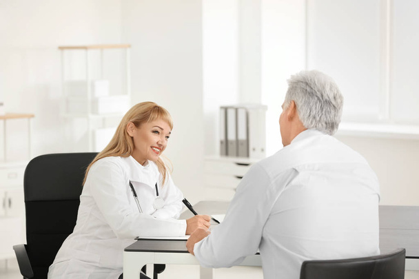 Female doctor consulting senior patient in clinic - Foto, immagini