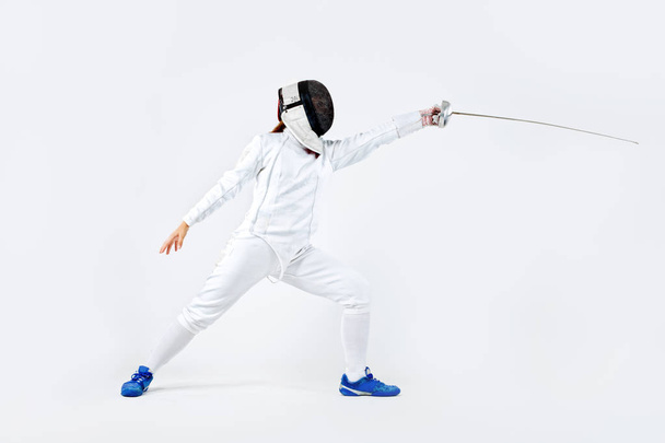Young fencer athlete wearing mask and white fencing costume. holding the sword. Isolated on white background - Fotó, kép