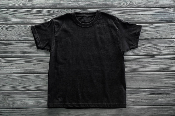 Blank black t-shirt on wooden background - Fotó, kép