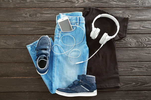 Stylish outfit with shoes and headphones on wooden background - Foto, Imagen