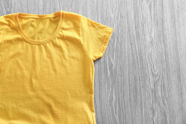 Blank yellow t-shirt on wooden background - 写真・画像