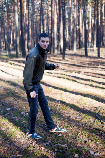 Um jovem de aparência criminosa em uma jaqueta de couro preto posando em uma floresta de outono
 - Foto, Imagem
