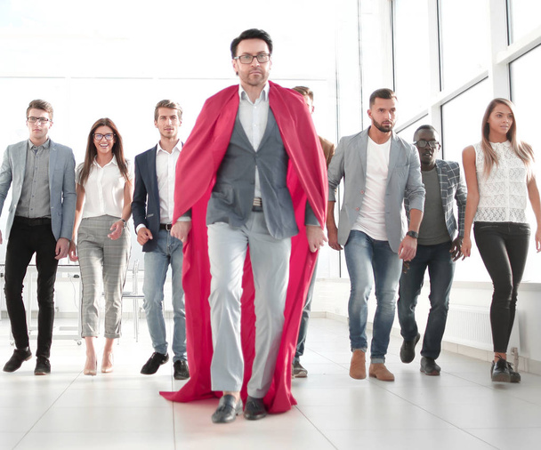 businessman in a superheros cloak is ahead of the business team - Photo, image