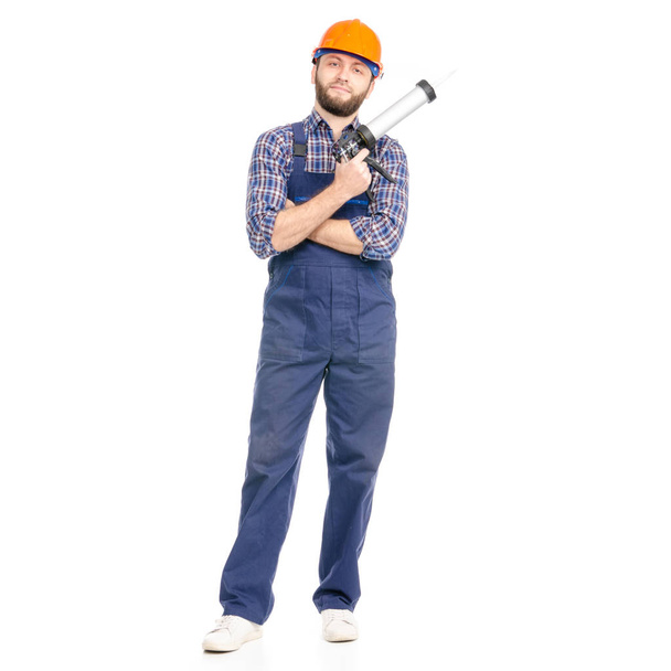 Young man builder industry worker hardhat with a silicone gun - Zdjęcie, obraz