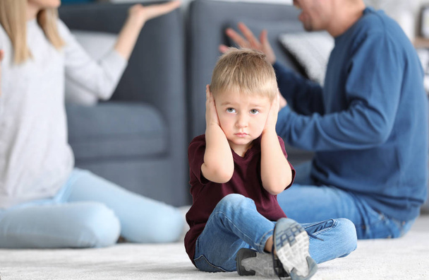 Sad little boy in room with quarreling parents. Family conflict - Foto, Bild