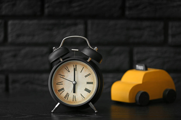 Reloj despertador con juguete de coche en mesa oscura
 - Foto, imagen