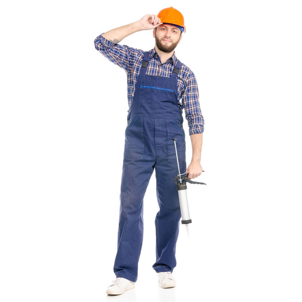 Young man builder industry worker hardhat with a silicone gun - Zdjęcie, obraz