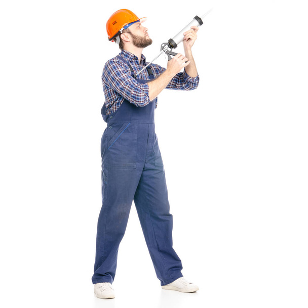 Young man builder industry worker hardhat with a silicone gun - Φωτογραφία, εικόνα
