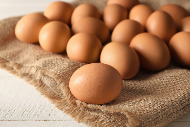 Сырые коричневые куриные яйца на мешковине
 - Фото, изображение