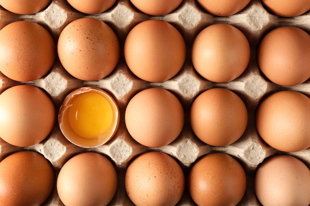 Тріщини і цілі курячі яйця в картонній упаковці, вид зверху
 - Фото, зображення